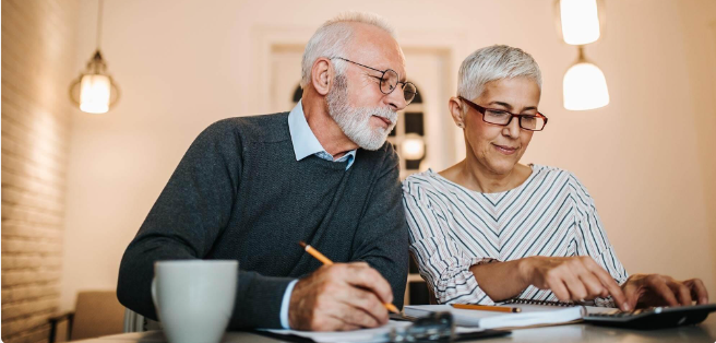 Seniorenpaar bespreekt financiële zaken aan tafel met pen en papier